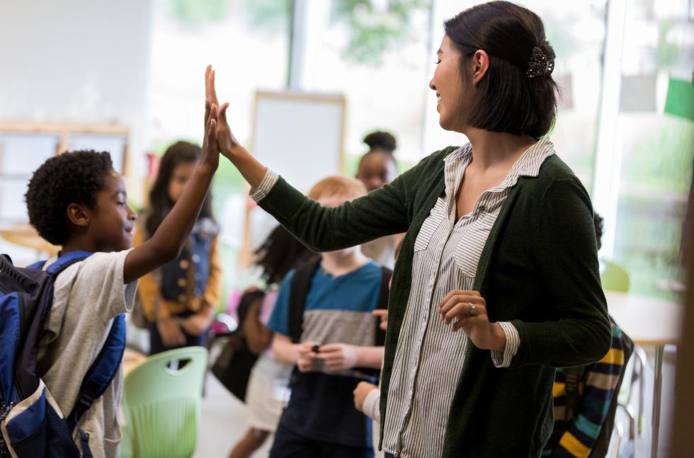 Lehrerin klatscht sich mit Schüler ab und lächelt