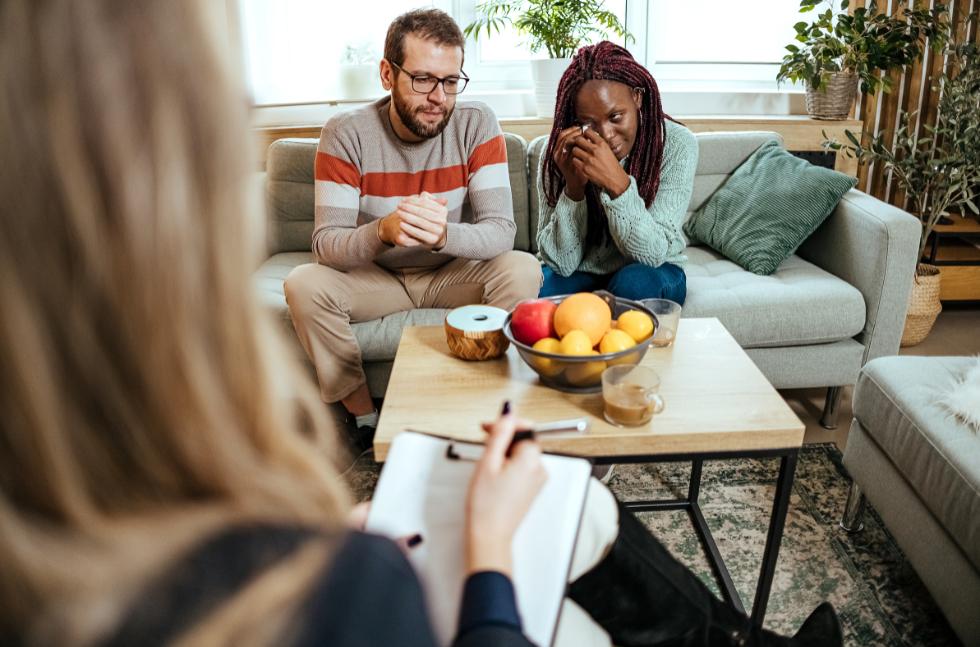 Familienberatung-in-Krisen-Elternberaterin-im-Anschnitt-Mutter-weint-Vater-schaut-traurig Familienberatung in Krisen: Mutter weint, Vater schaut traurig